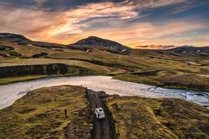 Four wheel drive vehicle parked by the big river crossing in the evening on remote rural at Icelandic Highlands photo