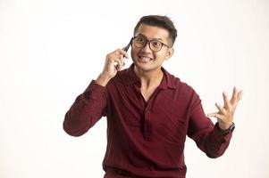 Smart Asian man using smartphone in studio background, handsome young Asian man smiling happily in formal shirt. using a smartphone to exchange or chat photo