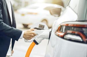 Chinese electric cars in Laos plug into electrical connectors to charge batteries Unknown man attaching wires to electric cars, electric cars, battery chargers, charging ports. photo