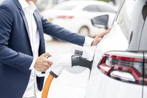 Chinese electric cars in Laos plug into electrical connectors to charge batteries Unknown man attaching wires to electric cars, electric cars, battery chargers, charging ports. photo