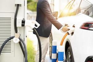 Chinese electric cars in Laos plug into electrical connectors to charge batteries Unknown man attaching wires to electric cars, electric cars, battery chargers, charging ports. photo