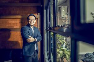 A mature business manager smiling confidently looks at the camera standing in the office at a team meeting photo