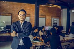 A mature business manager smiling confidently looks at the camera standing in the office at a team meeting photo
