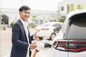 Chinese electric cars in Laos plug into electrical connectors to charge batteries Unknown man attaching wires to electric cars, electric cars, battery chargers, charging ports. photo