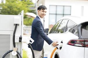 Chinese electric cars in Laos plug into electrical connectors to charge batteries Unknown man attaching wires to electric cars, electric cars, battery chargers, charging ports. photo