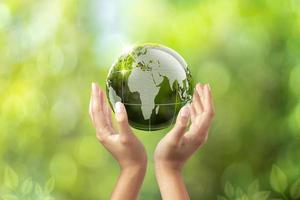 environmental conservation earth concept, woman lifting globe with both hands, earth in woman's hand green bokeh background and white light photo
