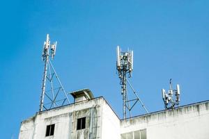 torre de comunicación con antenas en la parte superior del edificio y fondo de cielo azul brillante. foto