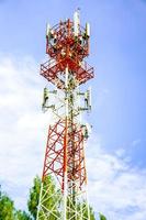 Telecoms tower with transmitter antenna on the bright blue sky background.
