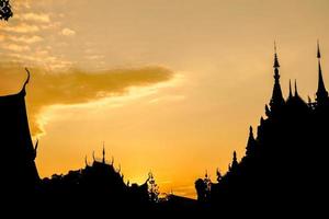 Closeup and crop silhouette of Thai temple on golden sun set sky background. photo