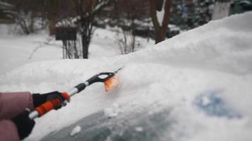 giovane donna nel rosa gonfio cappotto spazzole neve via auto video