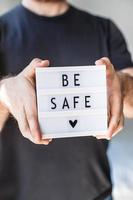 Man holding lightbox with text Be safe in his hand photo