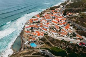 vista aérea por drones de azenhas do mar, un pequeño pueblo portugués situado al borde de un acantilado en una ubicación impresionante en la costa cerca de sintra foto