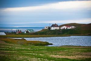 paisaje islandés con una pequeña ubicación en la costa del fiordo foto