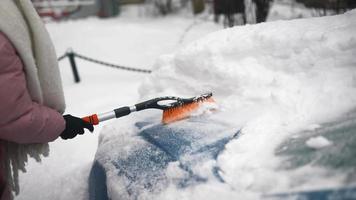 ung kvinna i rosa pösigt täcka borstar snö av bil video