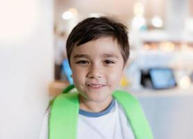 Portrait Kid looking at camera with smiling face standing alone with blurry payment counter background, Head shot happy Child boy standing at front of blurry image of toy shop in department store photo