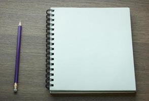 blank spiral notebook and pencil on dark wood background photo