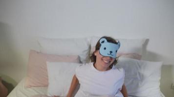 ung skön kvinna i säng sätter på sömn mask formad tycka om en Björn video