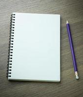 blank spiral notebook and pencil on dark wood background photo