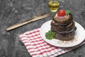 berenjenas a la parrilla en plato sobre fondo de madera negra. foto