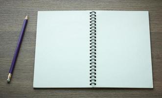 open spiral notebook and pencil on dark wood background photo