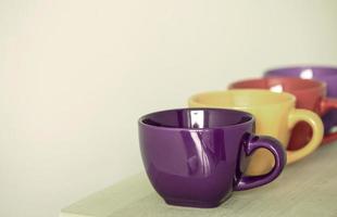 fila de tazas de colores en la mesa de madera foto