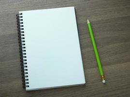 Cuaderno espiral en blanco y lápiz sobre fondo de madera oscura. foto