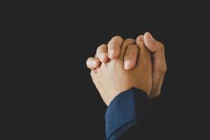 Hand folded prayer to god on dark in church concept for faith, spirituality and religion, woman person praying on holy bible in morning. Christian catholic woman hand with worship in black background. photo