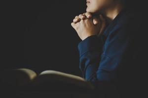 Hand folded in prayer to god on Holy Bible book in church concept for faith, spirituality and religion, woman person praying on holy bible in morning. christian catholic woman hand with Bible worship. photo