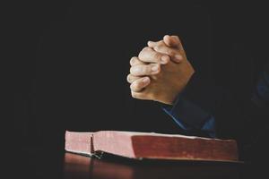 Hand folded in prayer to god on Holy Bible book in church concept for faith, spirituality and religion, woman person praying on holy bible in morning. christian catholic woman hand with Bible worship. photo