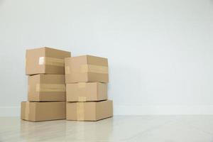 Stack of cardboard boxes for moving, Empty room with a white wall and cardboard boxes with unbranded barcode on the floor. Delivery of goods, shopping. Cardboard boxes on gray wall background. photo