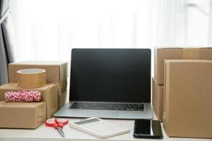 Equipments for SME online business, delivery business laptop, barcode, boxes, checking product on stocks or cardboard parcels. Small business working at home office. delivery service product at home. photo