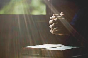 Hand folded in prayer to god on Holy Bible book in church concept for faith, spirituality and religion, woman person praying on holy bible in morning. christian catholic woman hand with Bible worship. photo