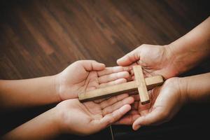 cruz en la oración de la mano a dios en la oscuridad en la iglesia concepto de fe espiritualidad y religión mujer persona orando en la santa biblia en la mañana. mujer católica cristiana mano con adoración en fondo negro. foto