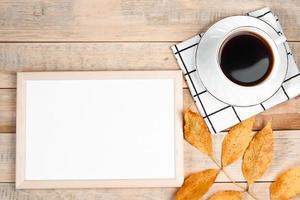 puesta plana de otoño. taza de café espresso caliente y hojas amarillas caídas sobre fondo de madera. maqueta de marco vacío para texto. concepto de la mañana. foto