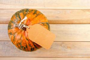 Harvest and autumn sale concept. Ripe pumpkin with label on a wooden background. Thanksgiving holiday. Copy space. photo