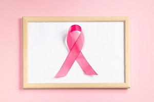 Pink ribbon on colored background. Breast Cancer Awareness Month symbol. Women's health care concept. Promotion of campaign to fight cancer. photo