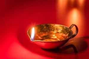 Burning diya oil lamp on red background. Celebrating the Indian traditional festival of light. Happy Diwali. photo