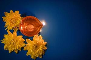 Happy Diwali. Diya oil lamps and yellow flowers on blue background. Celebrating the traditional Indian holiday of light. photo