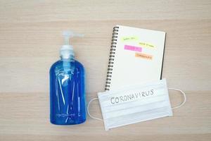 Top view of alcohol sanitizer gel and mask with message Coronavirus and notebook with memo about the pandemic Covid-19 and Coronavirus, health care and outbreak concept photo