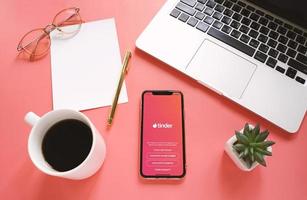 Flat lay of workspace desk and Apple iPhone XS with Tinder application on the screen. Tinder is a dating mobile app photo