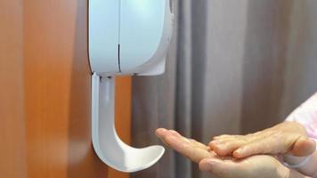 Senior patient woman washing her hand from automatic hand sanitizer in hospital, healthcare and prevention of pandemic Covid-19 and Coronavirus photo