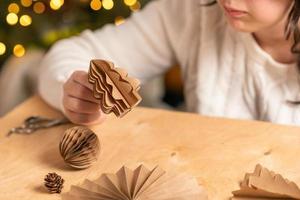 la niña hace decoraciones para árboles de navidad con papel con sus propias manos. paso 5. instrucción paso a paso