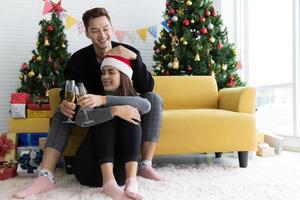 Beautiful young couple is holding glasses of champagne, smiling and affectionate while celebrating New Year at home photo