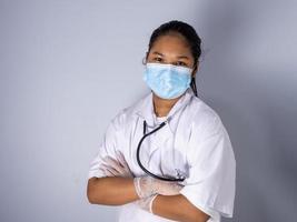 Studio portrait of a female doctor wearing a mask standing on a white background There was a slight light on his face. photo