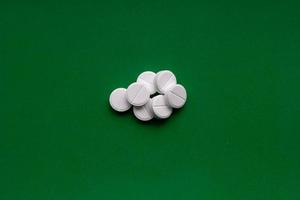 White squashed pills on green background. Crushed tablets. Medicine background. photo