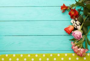 Frame of flowers and towels in polka dots on blue wooden background. Top view and selective focus. Copy space photo