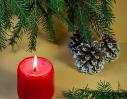 New Year's card, decorations. Candle, cones and fir branches on a beige background. New Year. Christmas photo