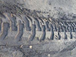 Marcas de ruedas de maquinaria pesada en suelo húmedo. Huella de neumático de tractor foto