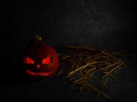 Still life for halloween. Pumpkin and straw on a black background. photo