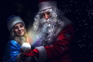 A snow maiden woman stands next to Santa photo